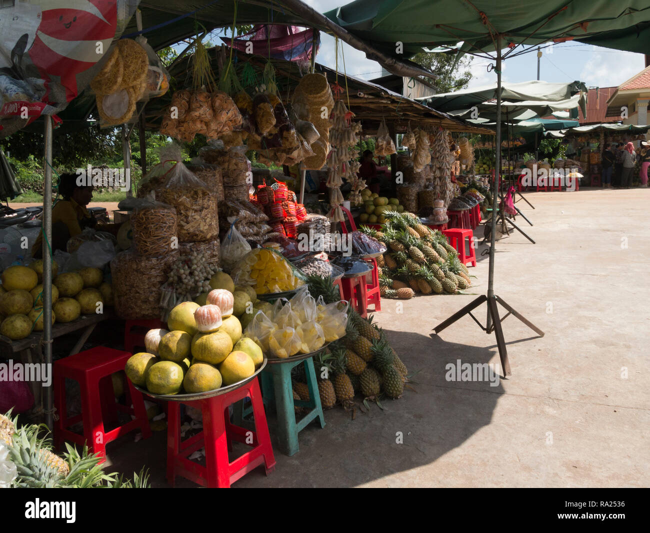 Stalls at Skuon Town Market selling dried and fresh fruit melons bananas dates pineapple mango and cashew nuts Cambodia Asia Stock Photo