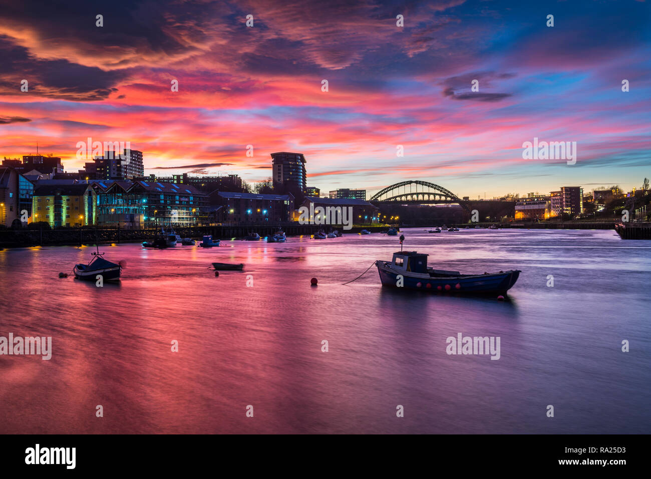 River Wear Fish Quay towards the iconic Wearmouth bridge, fishing boats in foreground, sunset producing a stunning array of colours & reflections Stock Photo
