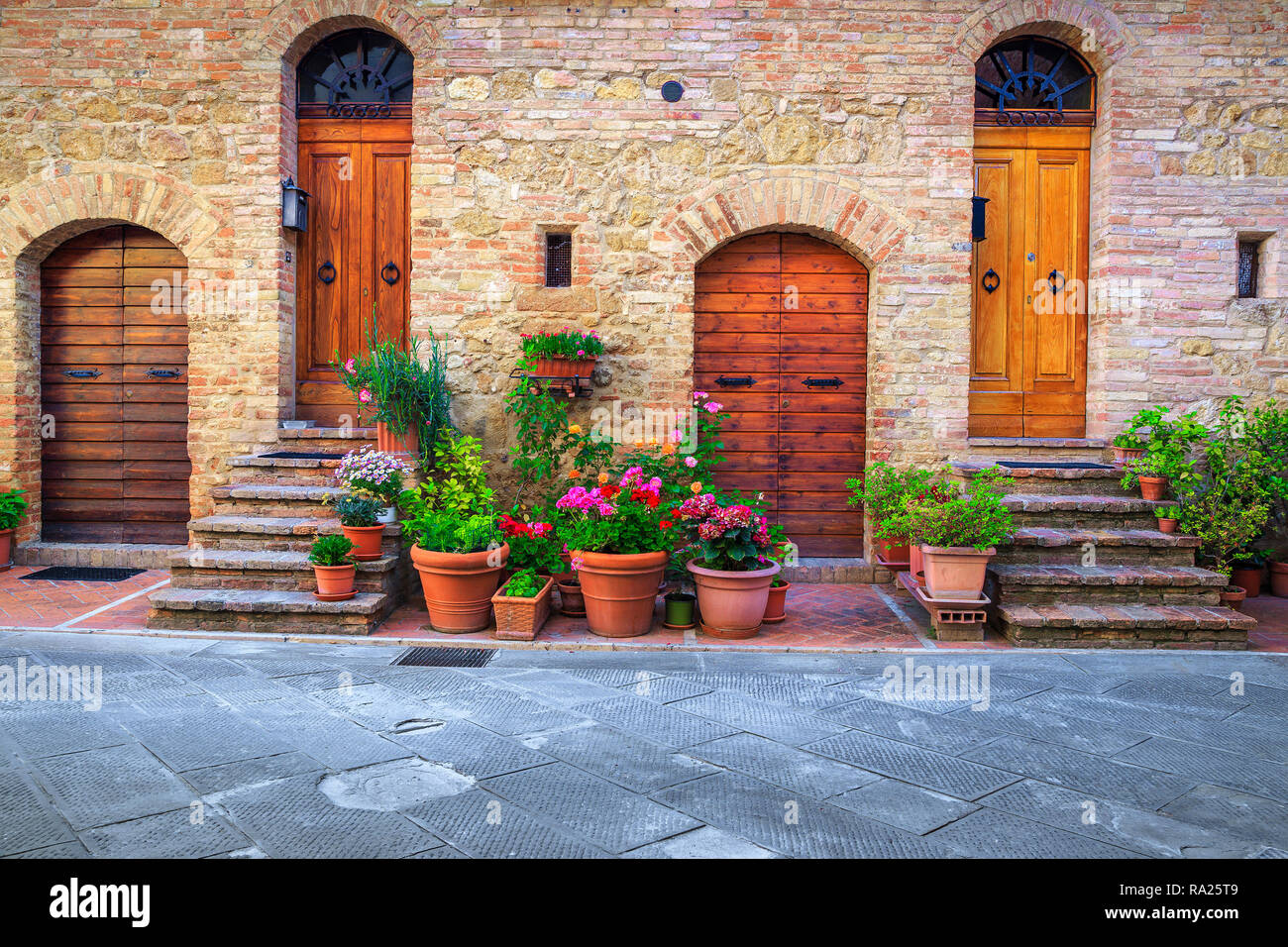 Traditional Tuscany architectural view. Fantastic entrance and paved street decorated with colorful flowers in Pienza, Tuscany, Italy, Europe Stock Photo