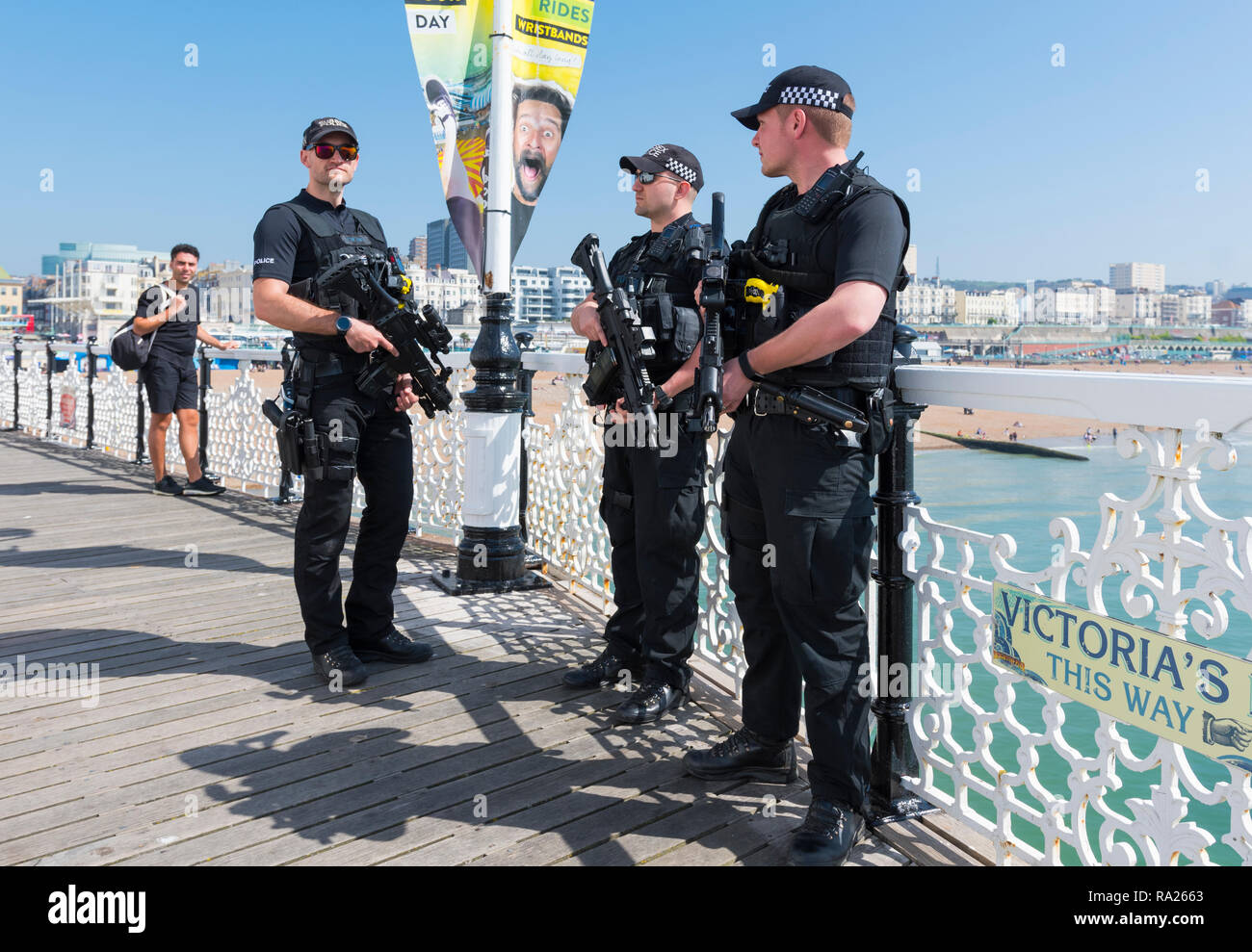 Armed police officers patrolling Brighton Pier in Spring in the UK. British police carrying guns at the seaside. Police carrying guns UK. Stock Photo