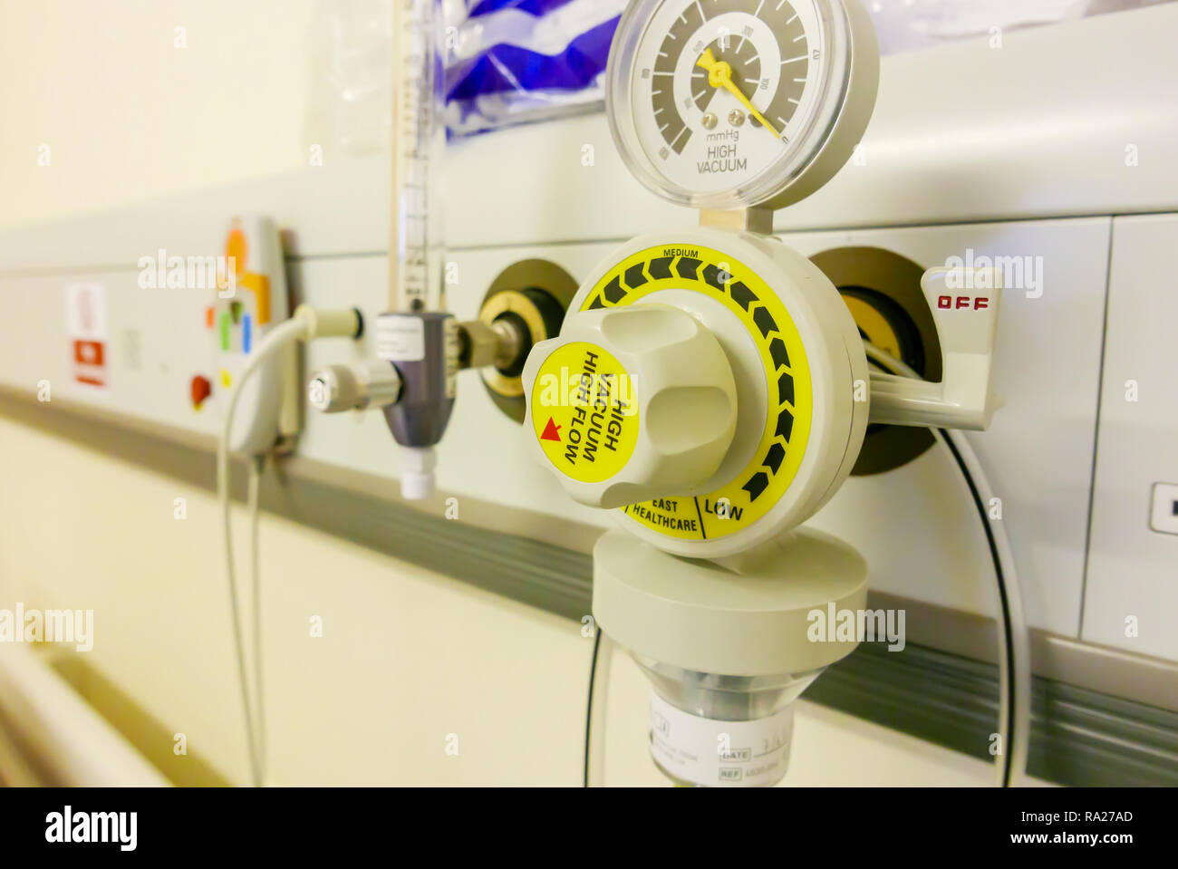 Bed head unit in a hospital ward showing a suction vacuum pressure gauge, an oxygen supply and a nurses call bell. Stock Photo