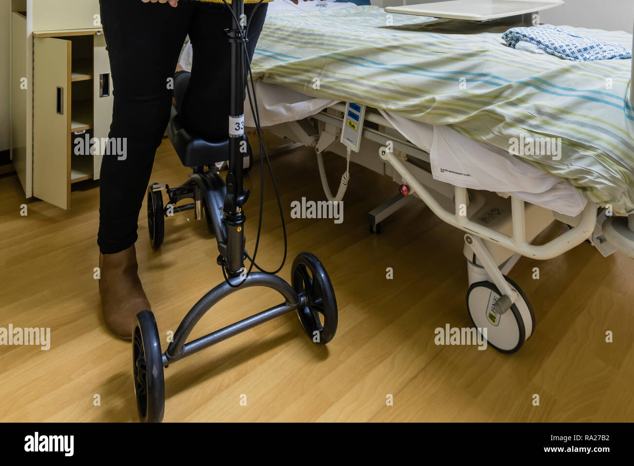 Hospital patient leaves using a Drive DeVilbiss Healthcare Height Adjustable Knee Scooter following foot surgery Stock Photo