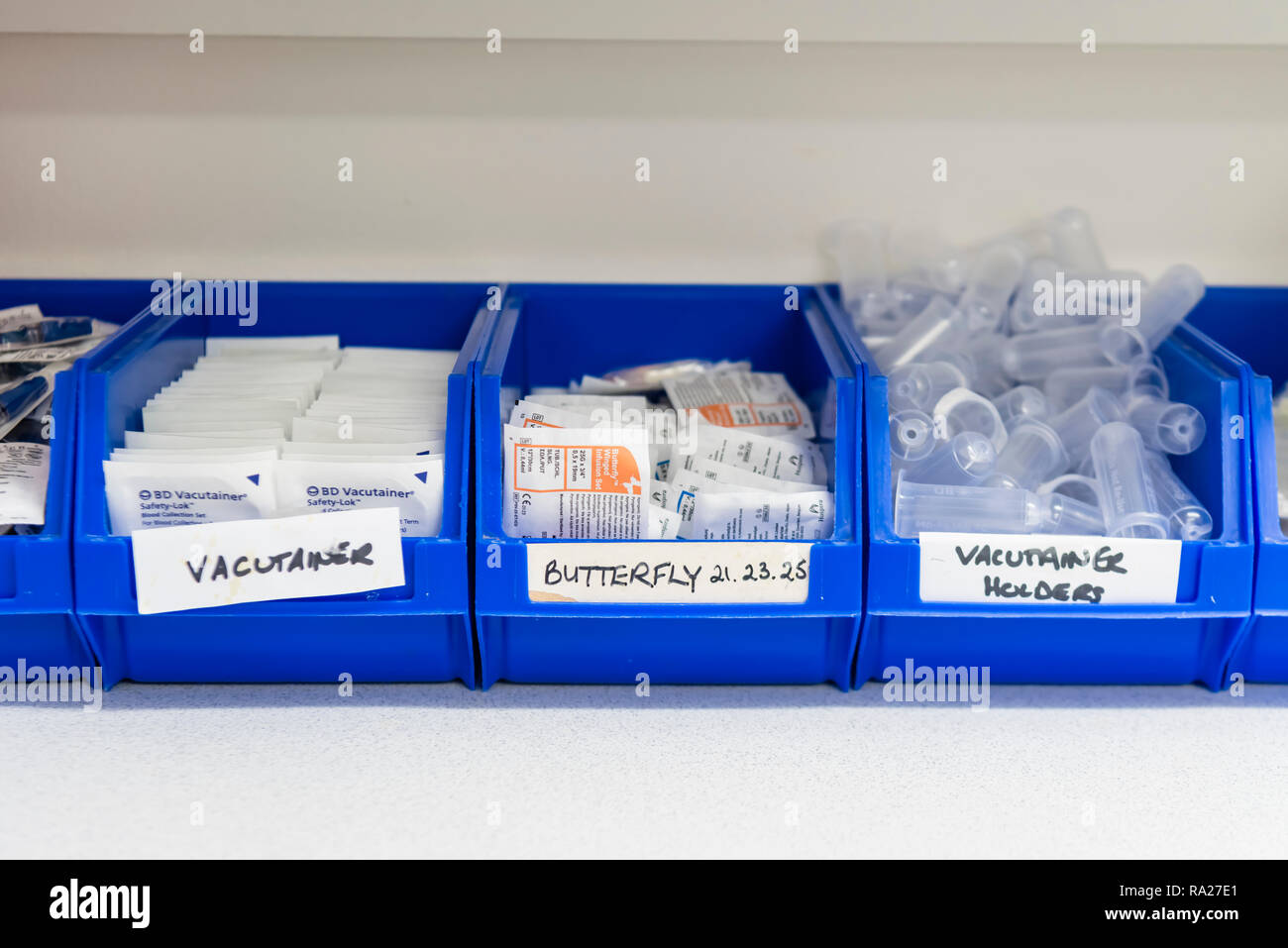 Plastic tubs containing medical equipment, including butterfly needles, vacutainers, torches etc for taking blood samples in a hospital treatment room Stock Photo