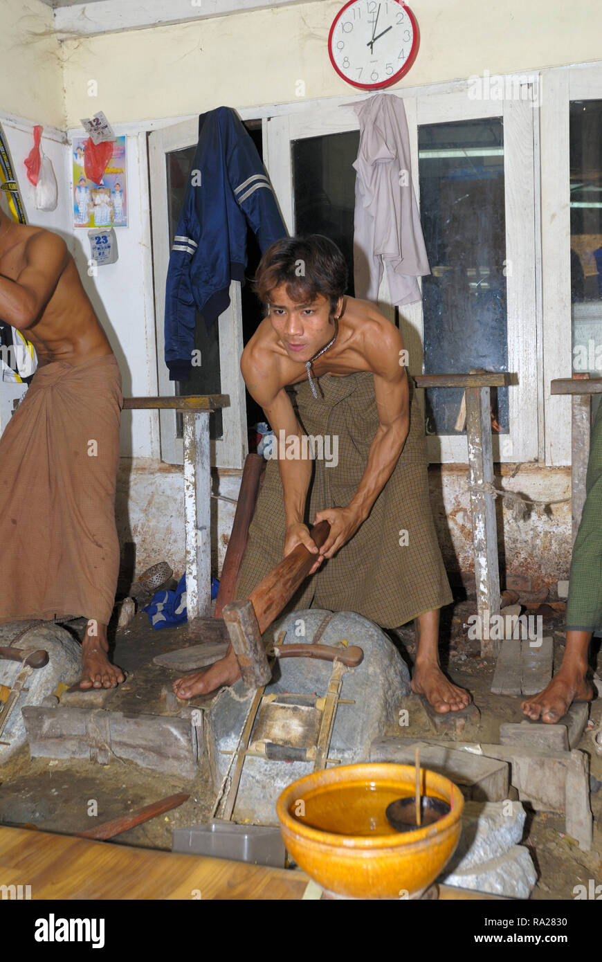 gold beating, young men beating with 3 kg beater beating hours on little in leather packed gold pieces Stock Photo