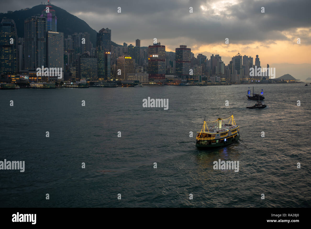 The Star Ferry Harbour cruise and Aqua Luna tourist junk ply their nightly trade against the spectacular backdrop of Hong Kong Island Stock Photo