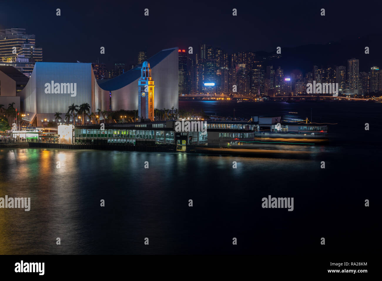 The Tsim Sha Tsui Star Ferry piers at night with views of the Clock Tower and Cultural Centre,  and across to Causeway Bay on Hong Kong Island Stock Photo