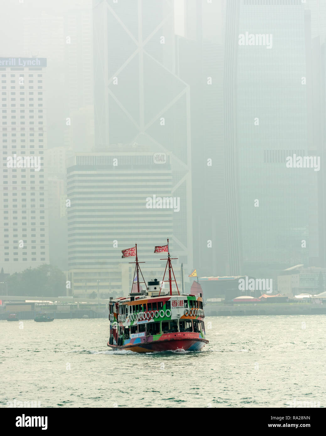 The colourful 'Night Star' Star Ferry plying its trade from Central to Tsim Sha Tsui on Kowloon, with the towers of Hong Kong Island as a backdrop. Stock Photo