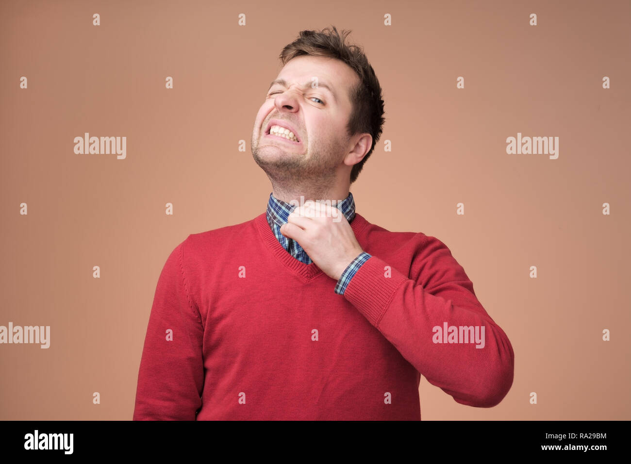 Young europeam man in red sweater feeeling uncomfortable. Stock Photo