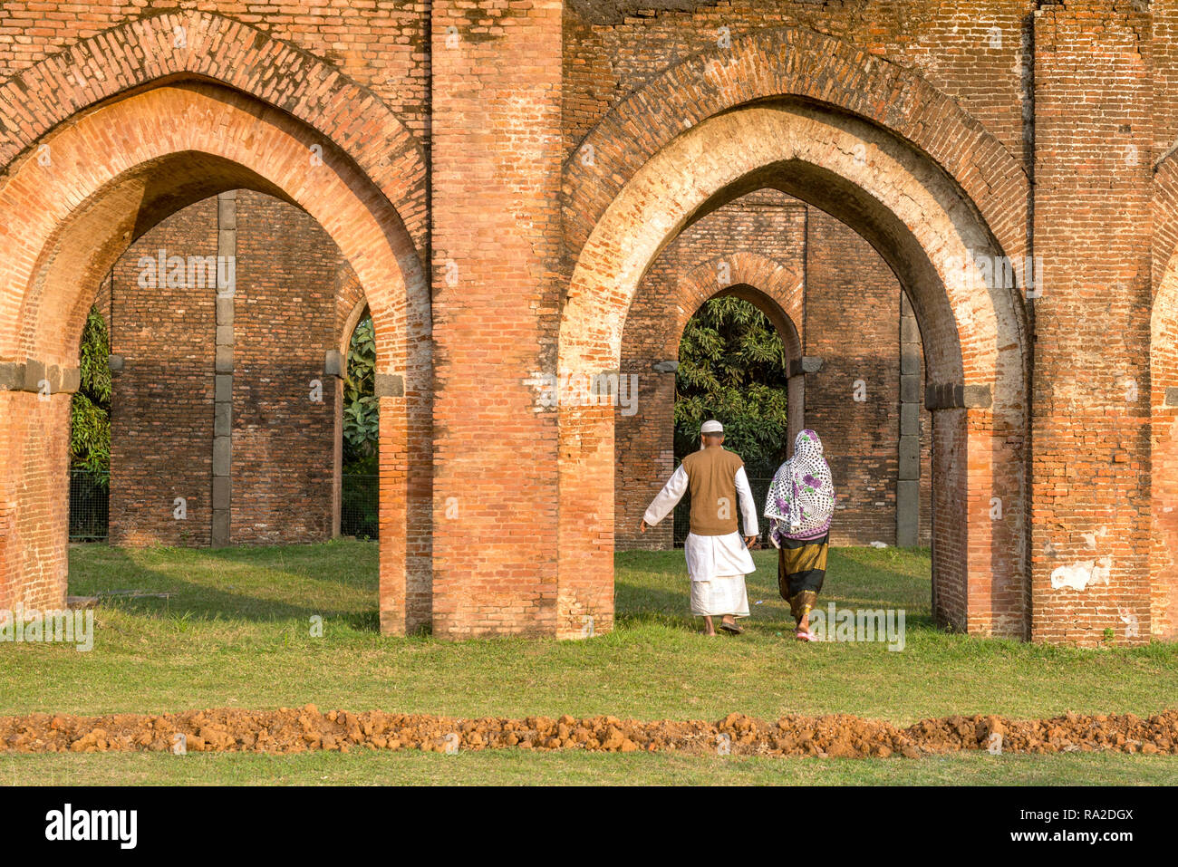 PANDUA, WEST BENGAL, INDIA, Elderly muslim couple strolling through the remains of the Adina-mosque in warm evening light. Stock Photo