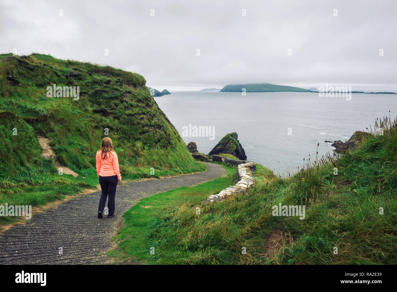 Young woman walks along pathway surrounded by irish landscape Stock Photo