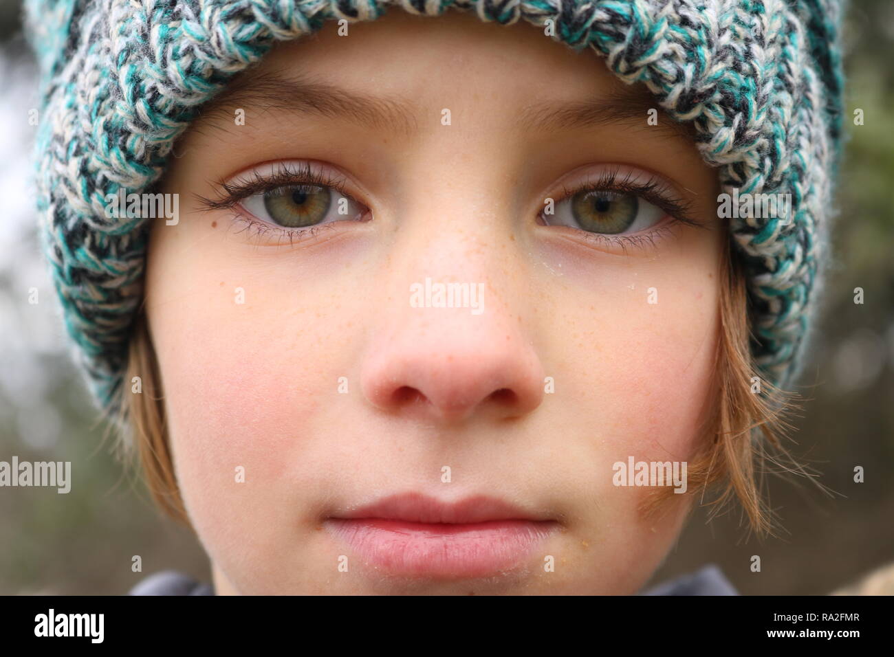 Closeup of a green eyed girl with a pensive stare wearing a winter hat Stock Photo