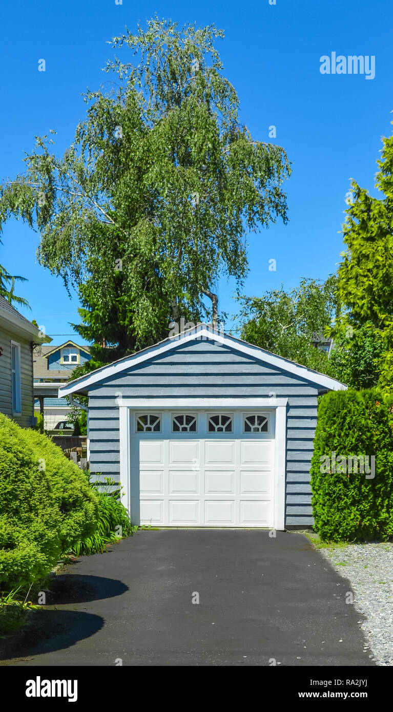 Stand along single garage on a back yard with asphalt driveway. Stock Photo