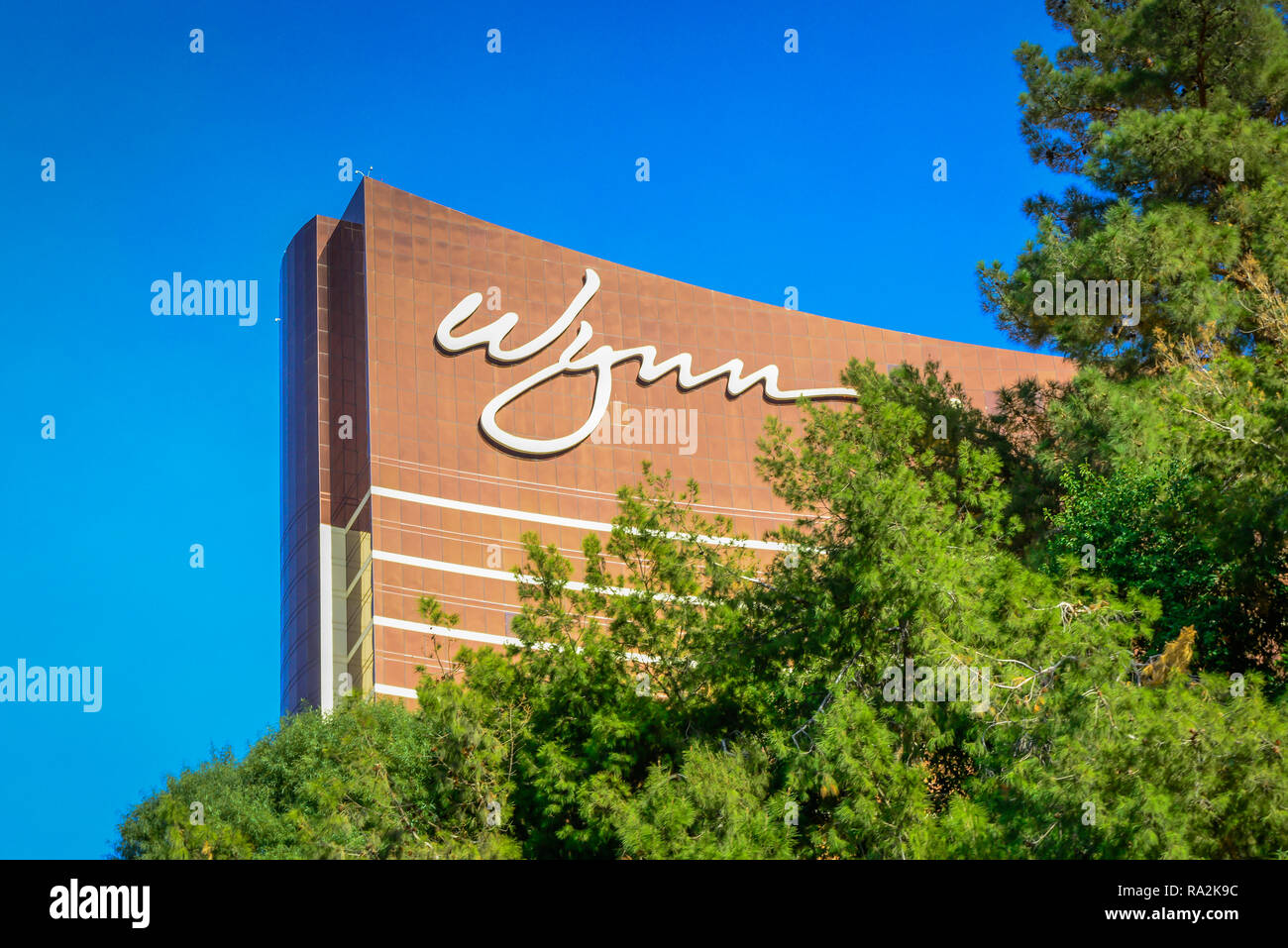 A cropped closeup of the signage on the distinctive bronze facade of the Wynn Resort Hotel and Casino surrounded by trees on the strip in Las, Vegas,  Stock Photo