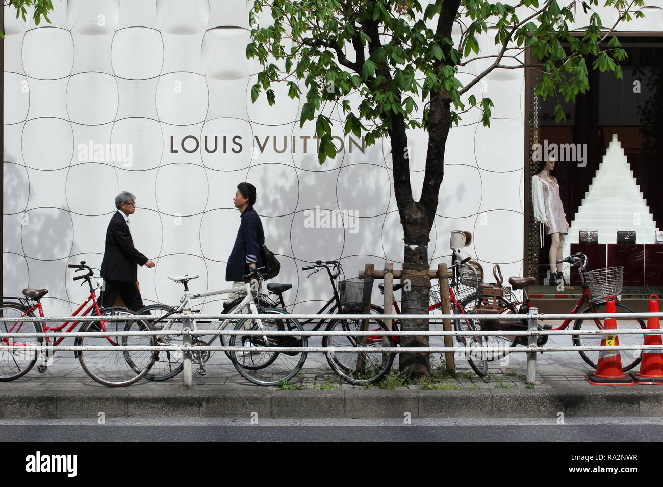 Pedestrians walking by the side of a large Louis Vuitton store in Ginza with a distinctive Jun Aoki-designed metallic facade. Stock Photo