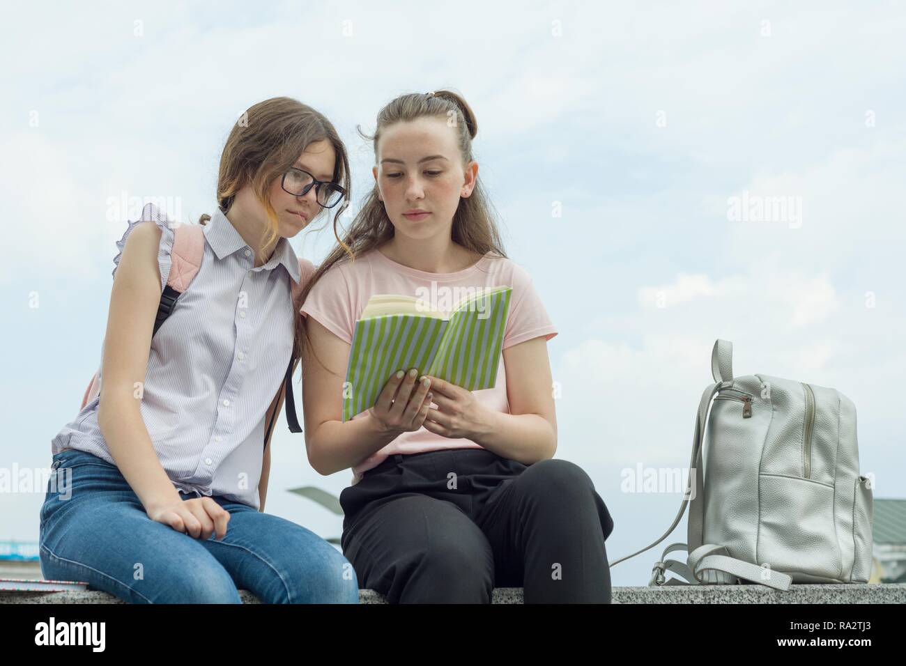 Outdoor portrait of two young beautiful girls students with backpacks ...
