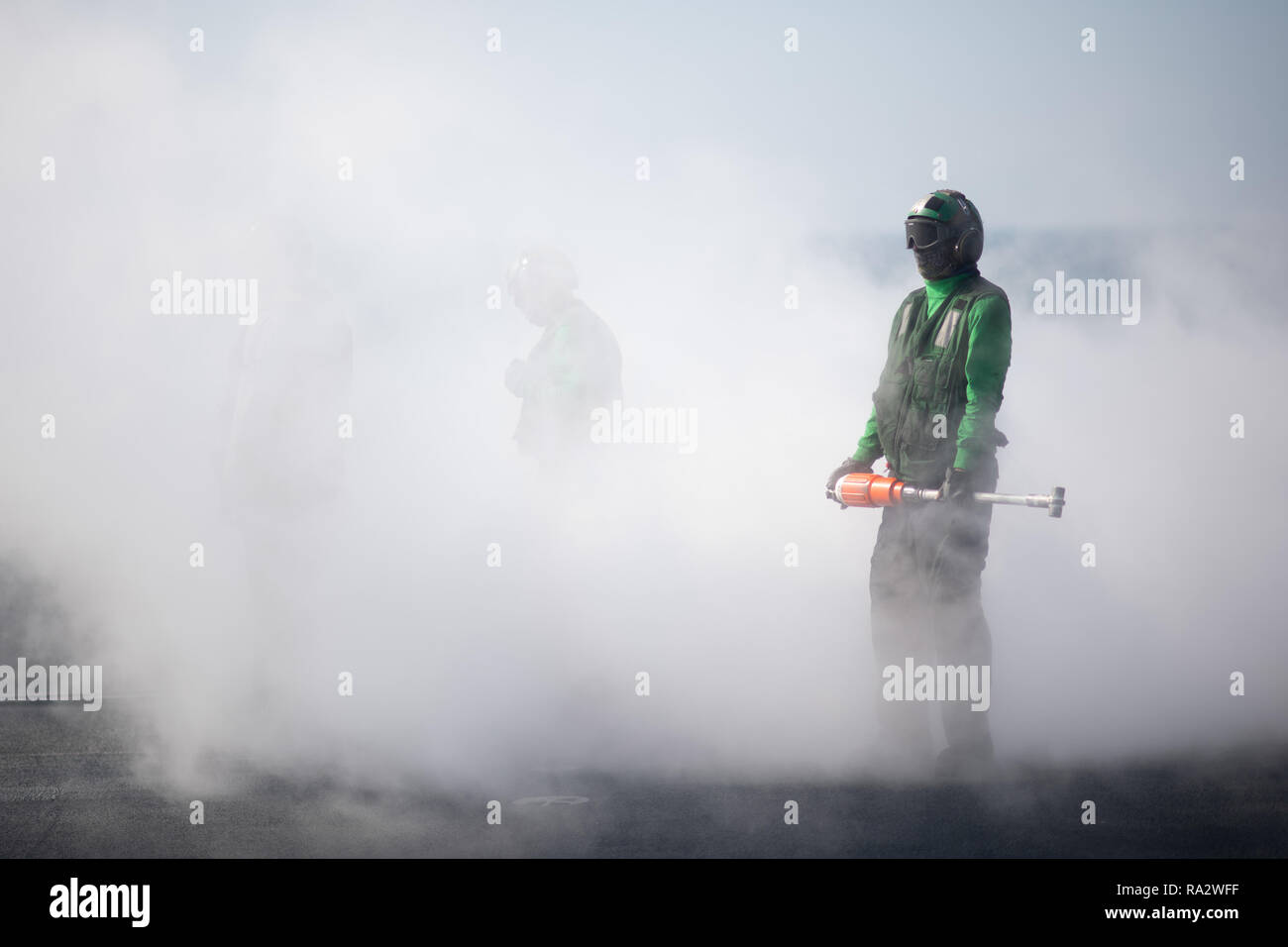 A U.S. Sailor prepares to attach a holdback bar to an aircraft before