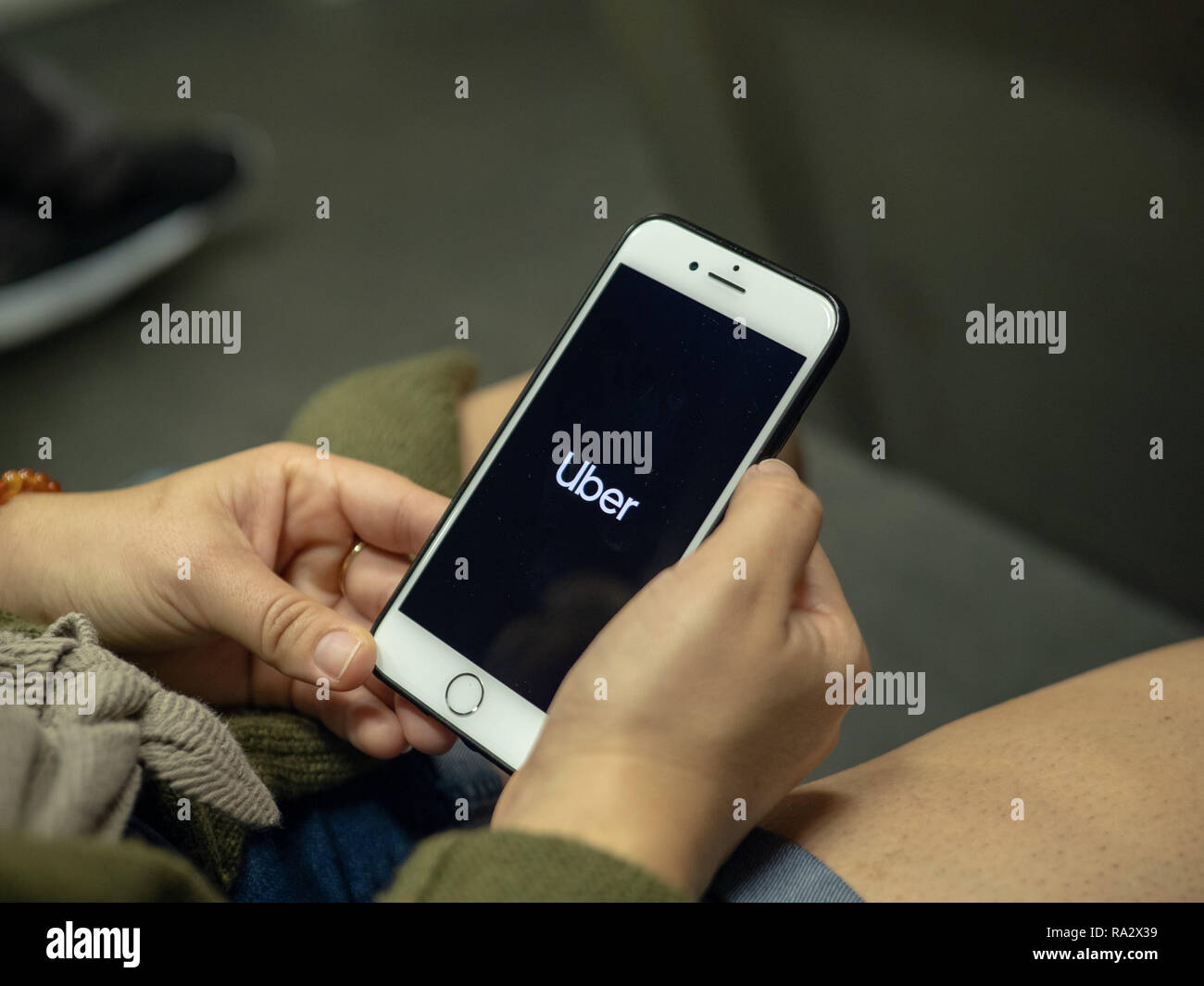 Woman uses Uber mobile app on iPhone while commuting on subway train ...