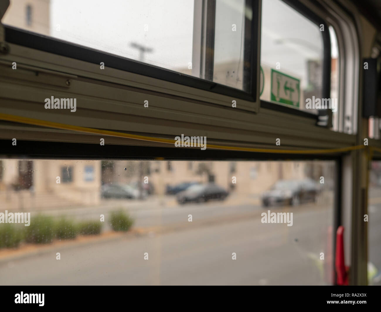 Yellow bus pull cord perched on top of window with city zooming Stock Photo Alamy