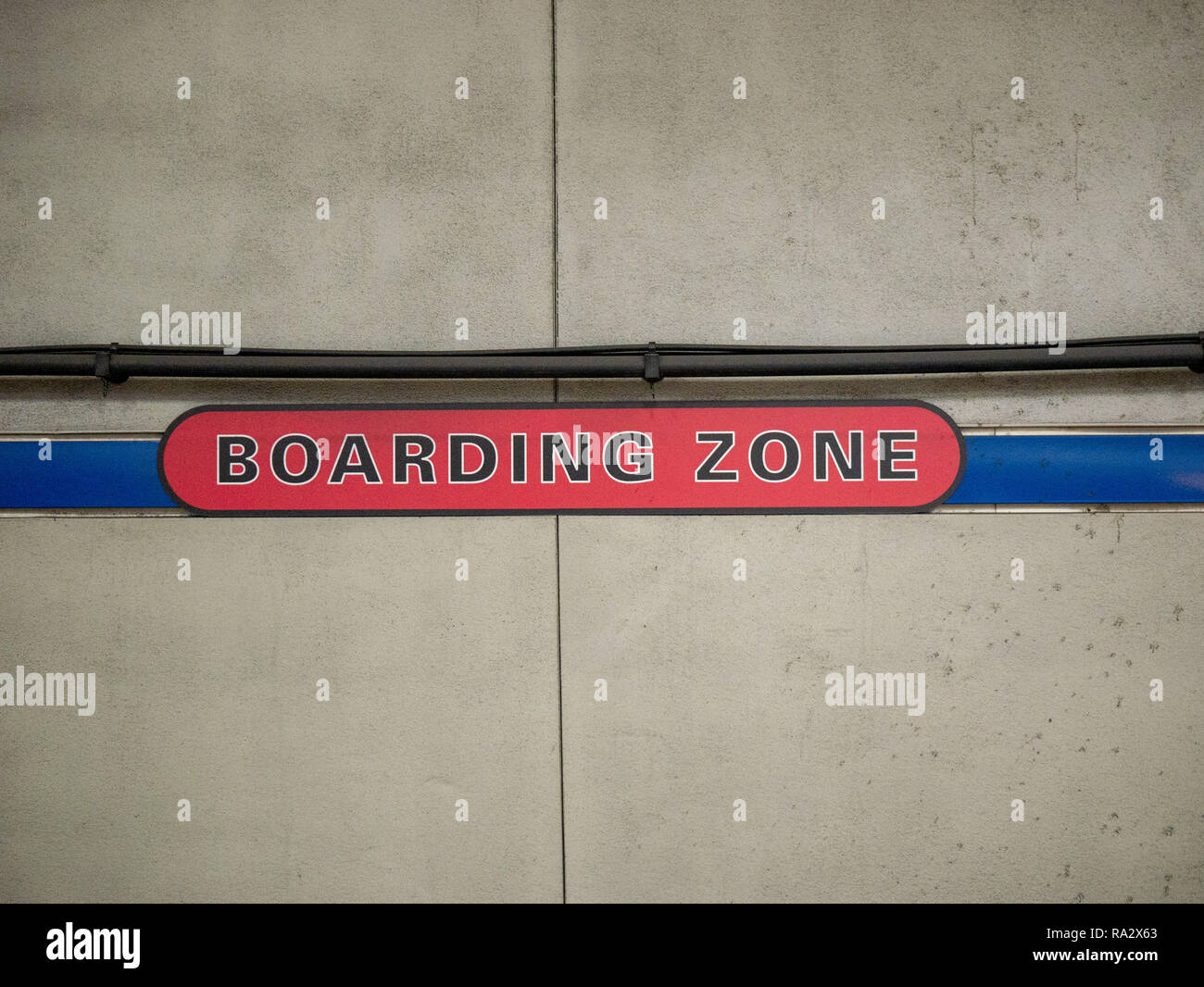 Red boarding zone sign on concrete wall in subway station Stock Photo