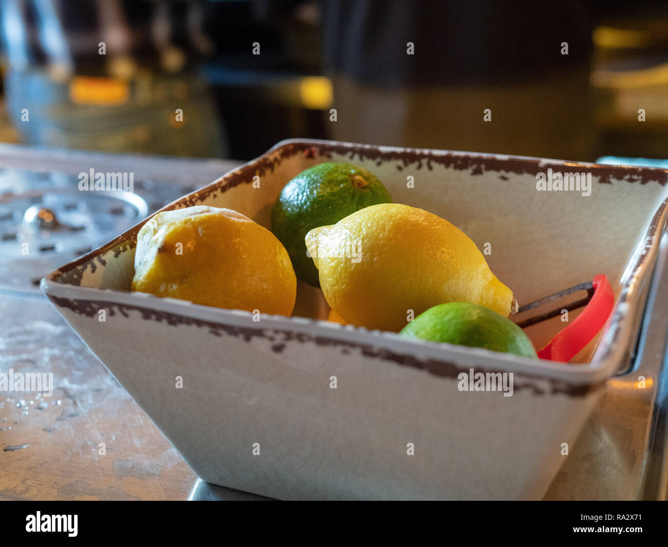 https://c8.alamy.com/comp/RA2X71/lemons-and-limes-with-peeler-sitting-in-bowl-of-a-bar-for-bartenders-to-make-cocktails-RA2X71.jpg