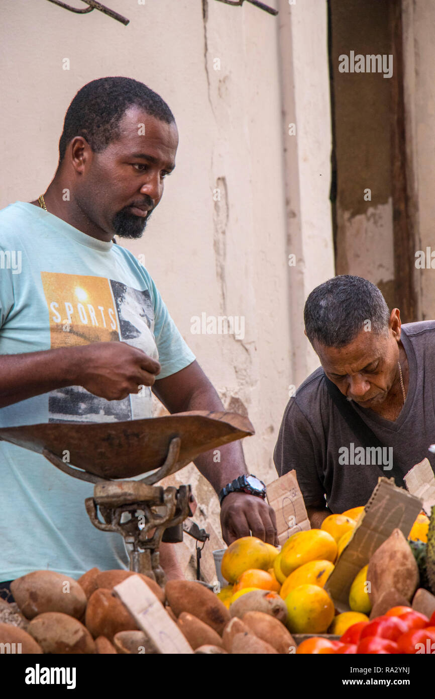 cuban market trader weighs vegetables in street in Havana, Cuba