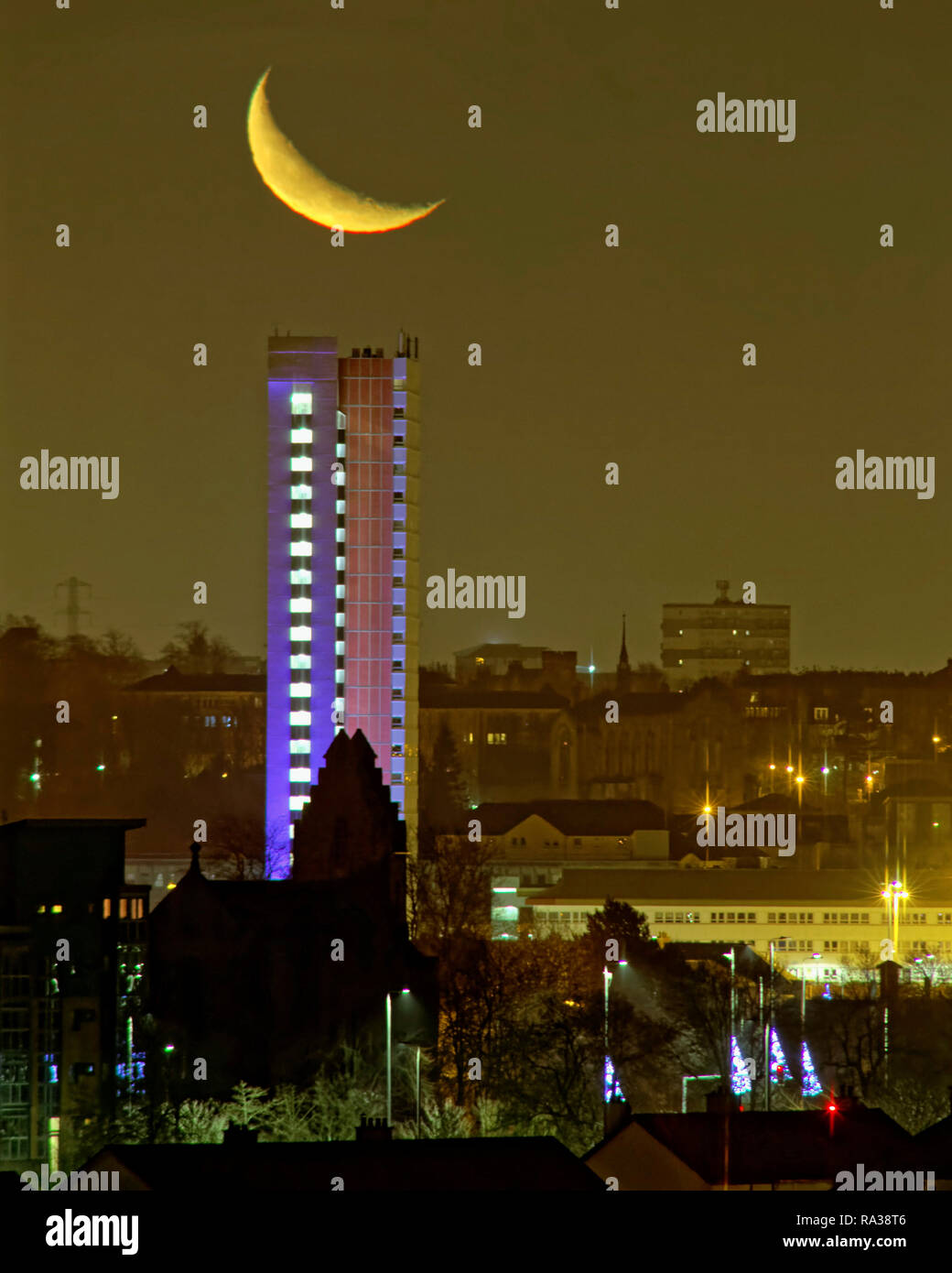 Glasgow, Scotland, UK, 1st January, 2019. UK Weather:  A mild new year saw the basis for the forthcoming beast from the east as a clear sky saw the crescent moon visible above the west end of the city and the highest listed building in Scotland, Anniesland Court Tower which is itself lit up for aesthetic value. Credit Gerard Ferry/Alamy Live News Stock Photo
