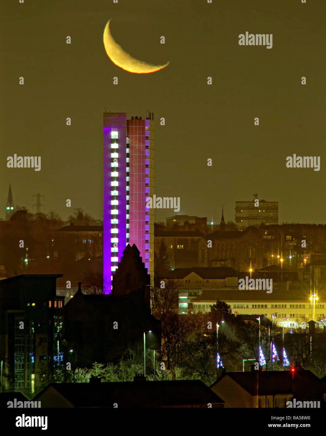 Glasgow, Scotland, UK, 1st January, 2019. UK Weather:  A mild new year saw the basis for the forthcoming beast from the east as a clear sky saw the crescent moon visible above the west end of the city and the highest listed building in Scotland, Anniesland Court Tower which is itself lit up for aesthetic value. Credit Gerard Ferry/Alamy Live News Stock Photo