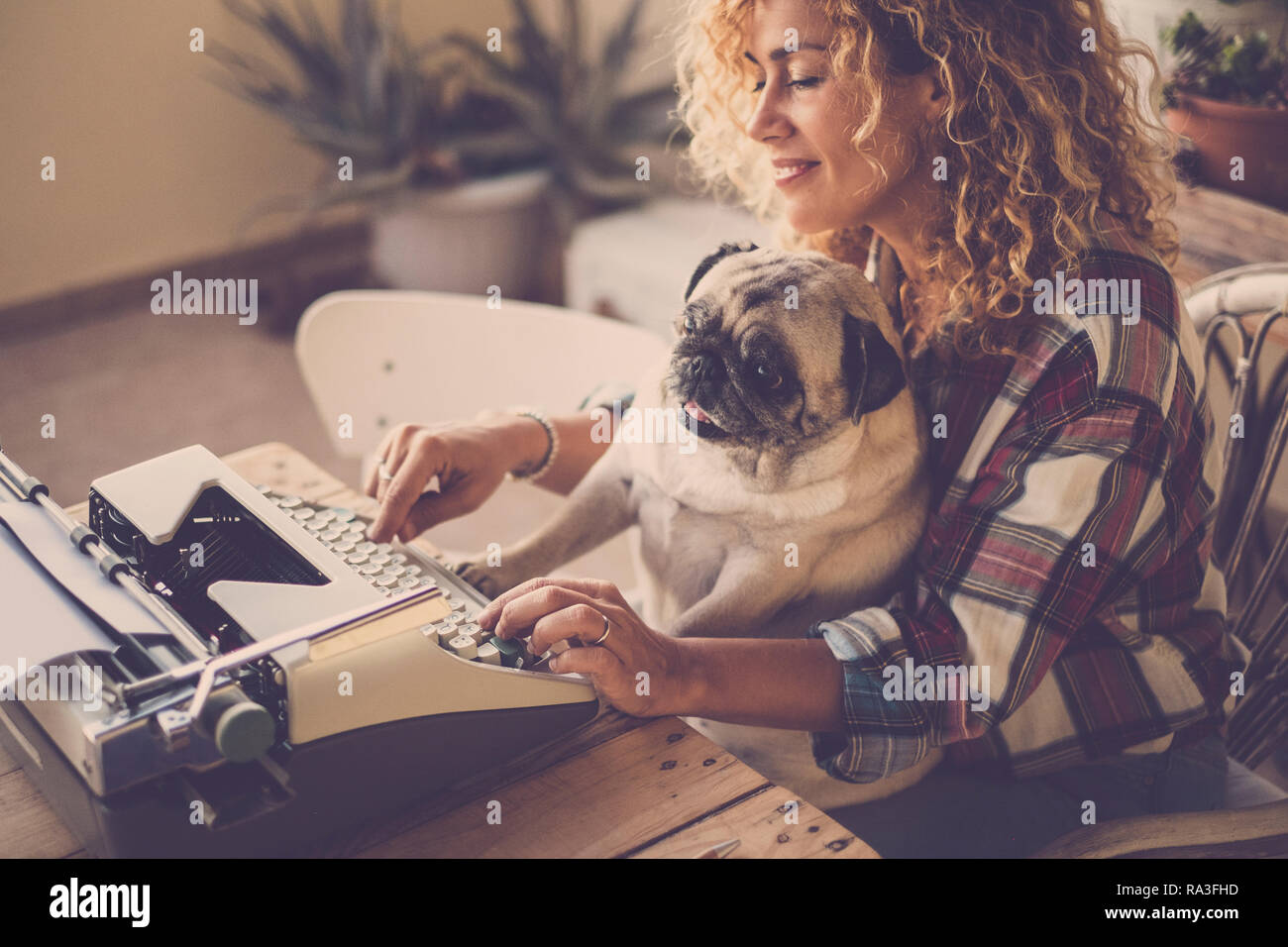 Funny scene with beautiful hipster curly blonde lady working and typing on  old typewriter writing a blog or book while her best friend love old dog pu  Stock Photo - Alamy
