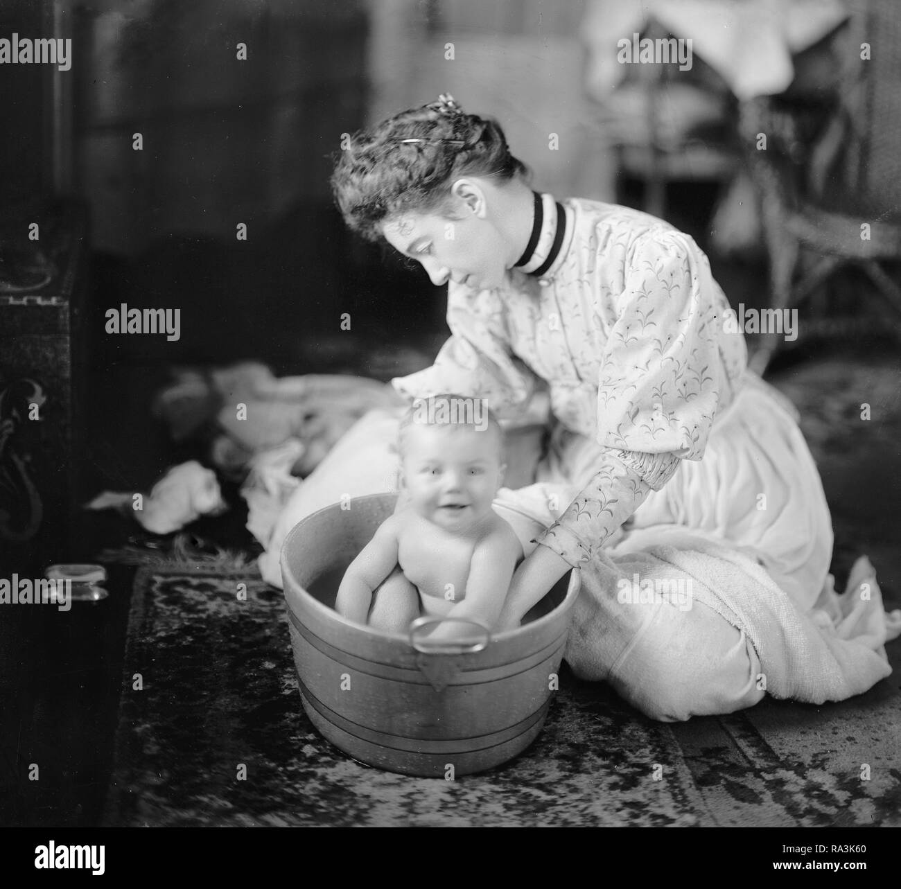 Early 1900s mother giving baby a bath Black and White Stock Photos