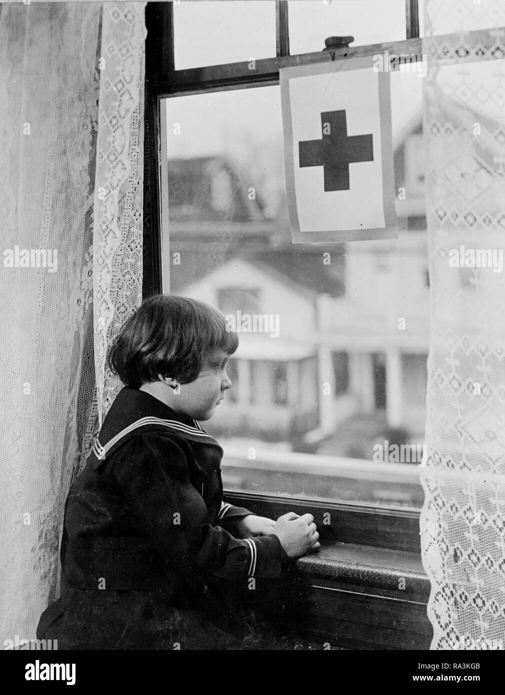 Red Cross - Little girl looking out window ca. 1910-1920 Stock Photo
