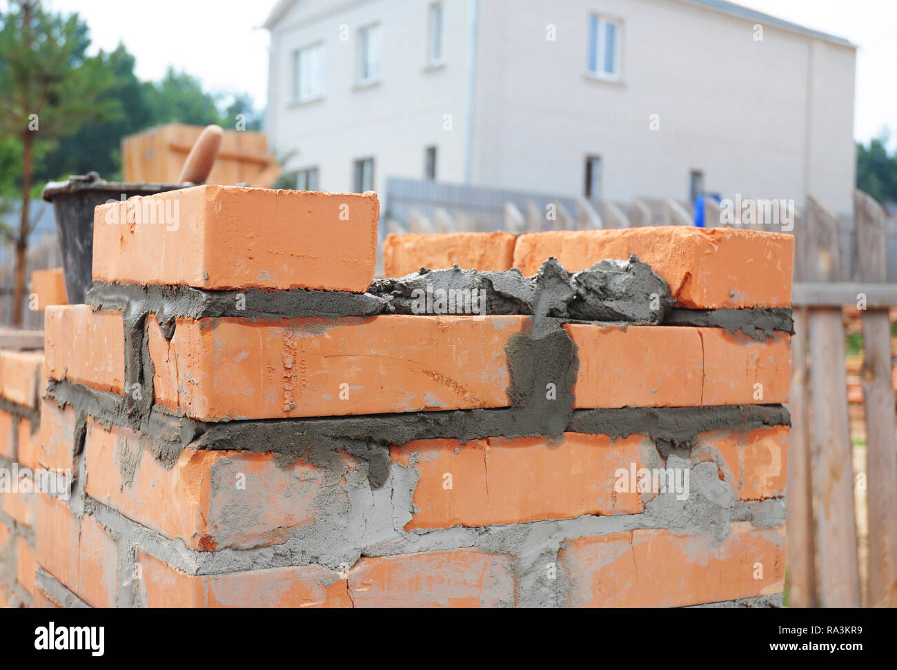Bricklaying house brick wall. Close up on laying bricks with concrete. Stock Photo