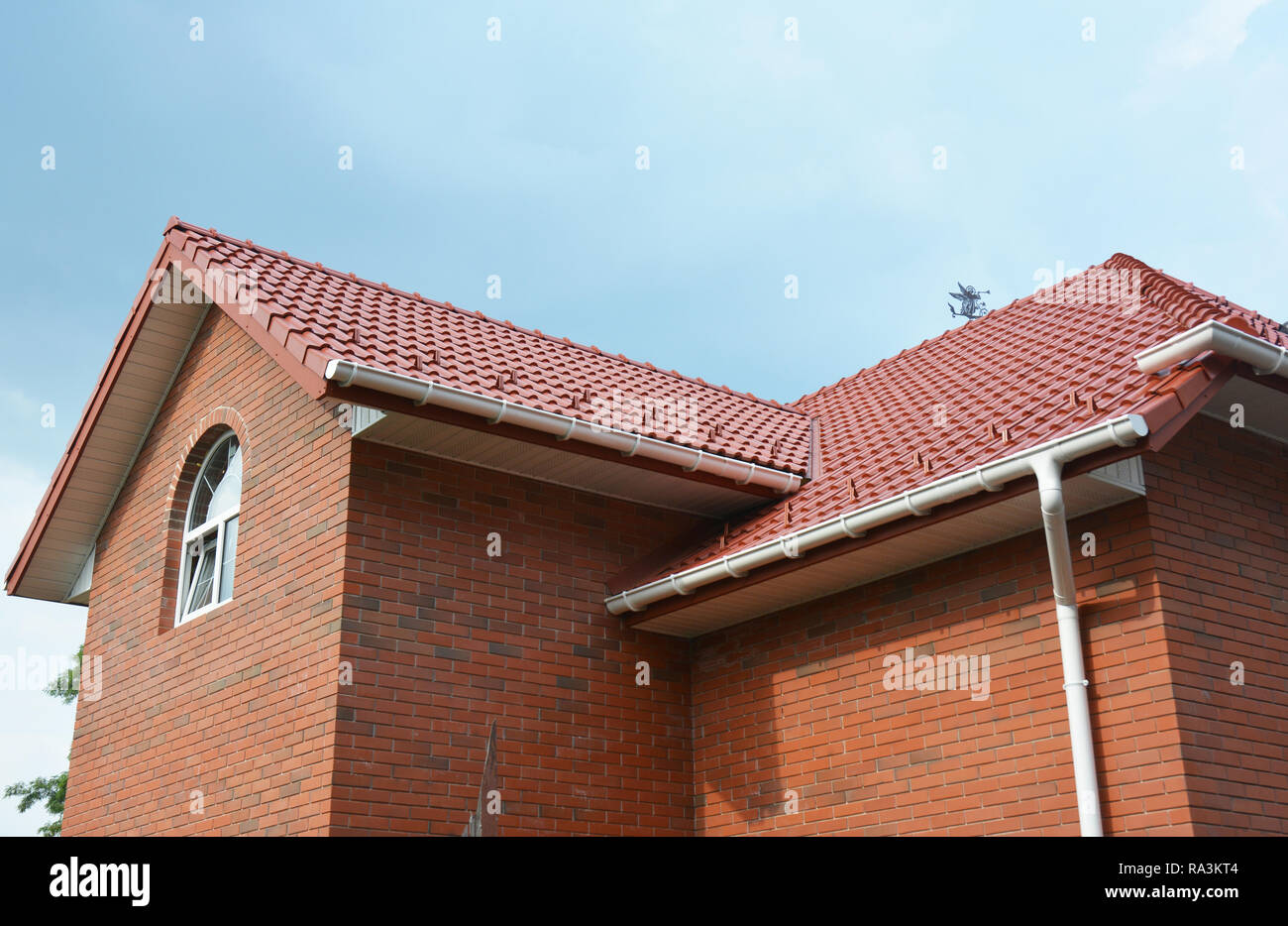 Rain gutter pipe system. Close up on attic brick house with clay roof