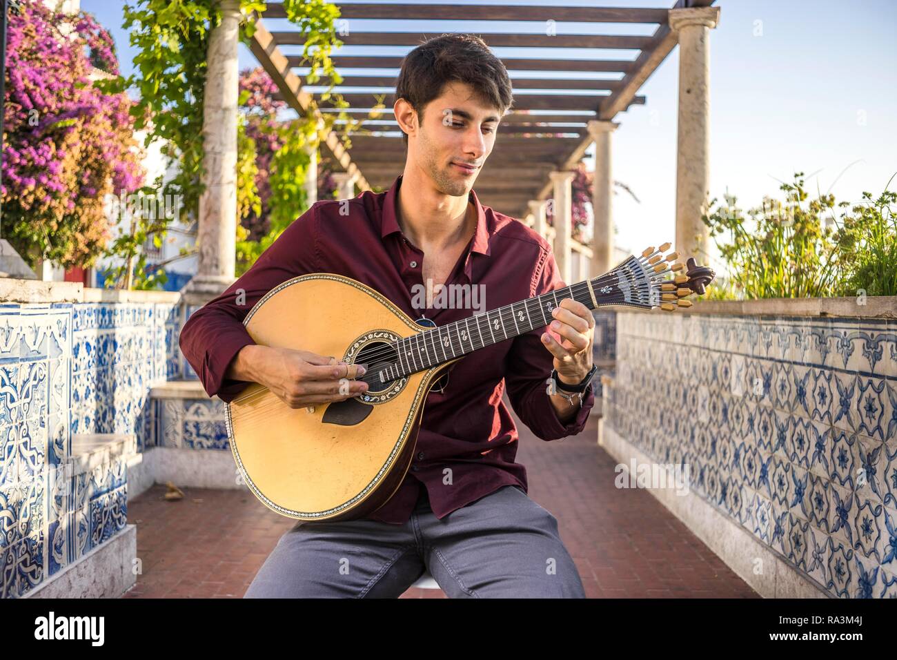 Fado musician playing on portuguese guitar under pergola in Alfama, Lisbon, Portugal Stock Photo