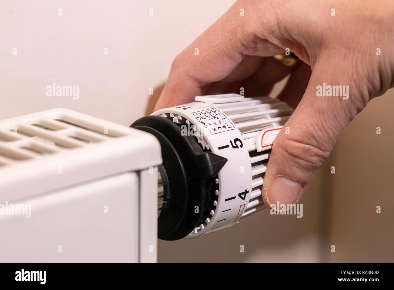 Hand adjusts the temperature at a thermostat of the heating, Bavaria, Germany Stock Photo
