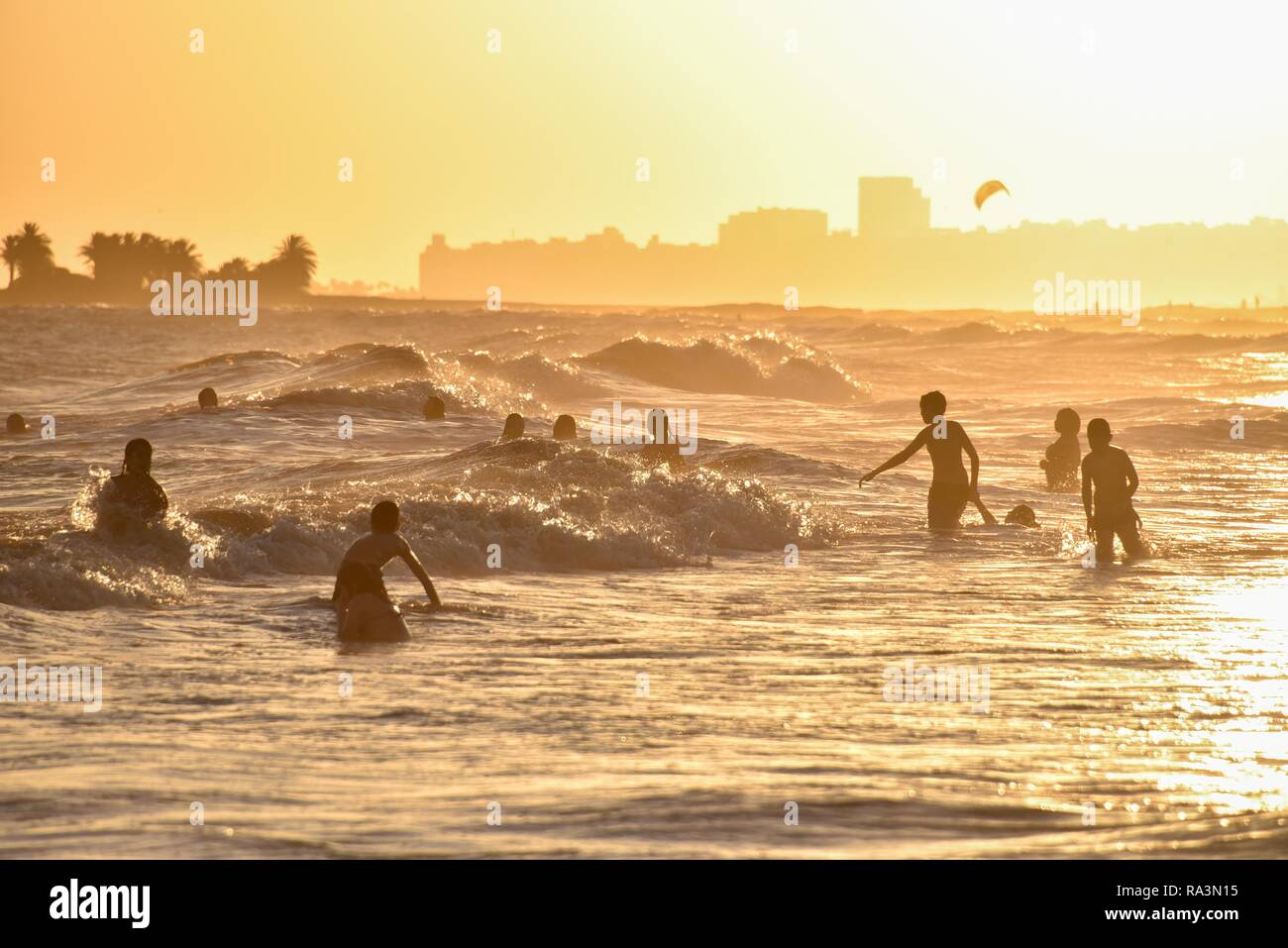 Many people bathing on the beach at sunset, beach Rambla, Montevideo, Uruguay Stock Photo