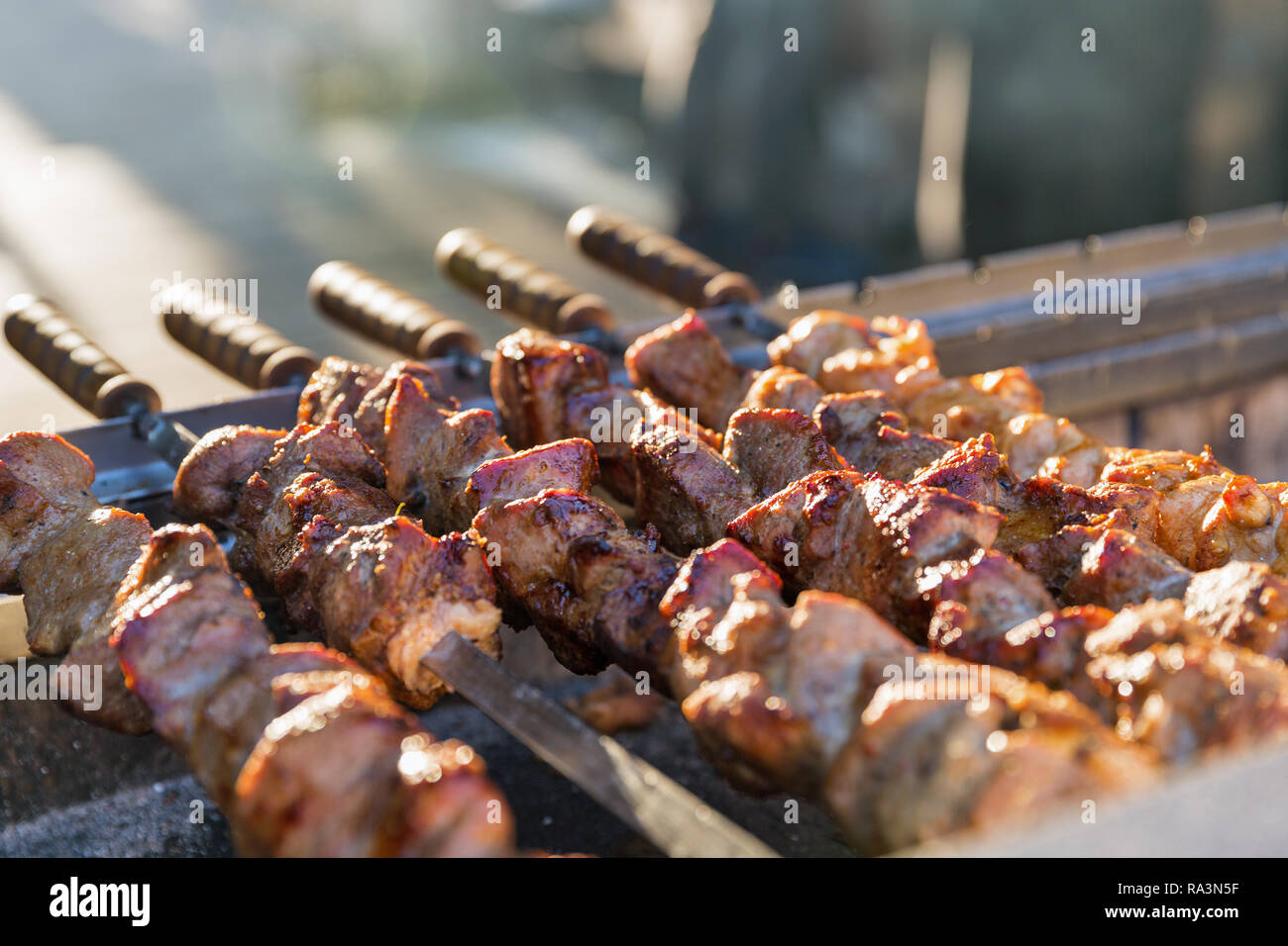 Barbecue on the grill closeup. Shashlik made of cubes of meat on the skewers during of cooking on the mangal over charcoal outdoors. Stock Photo