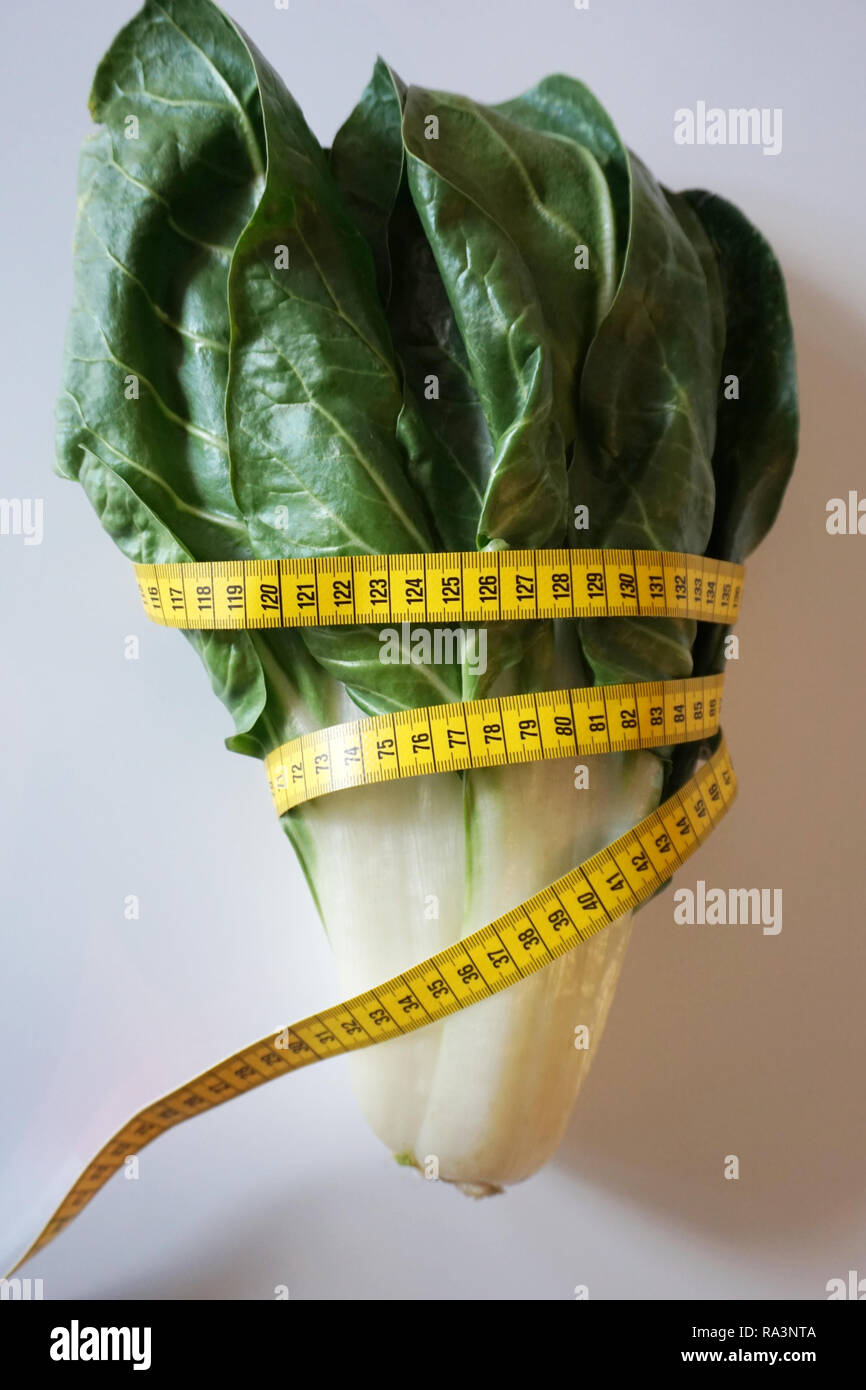 A bunch of fresh organic swiss chard green leaves wrapped with a tape measure. Diet, healthy food and detox after holiday concept Stock Photo