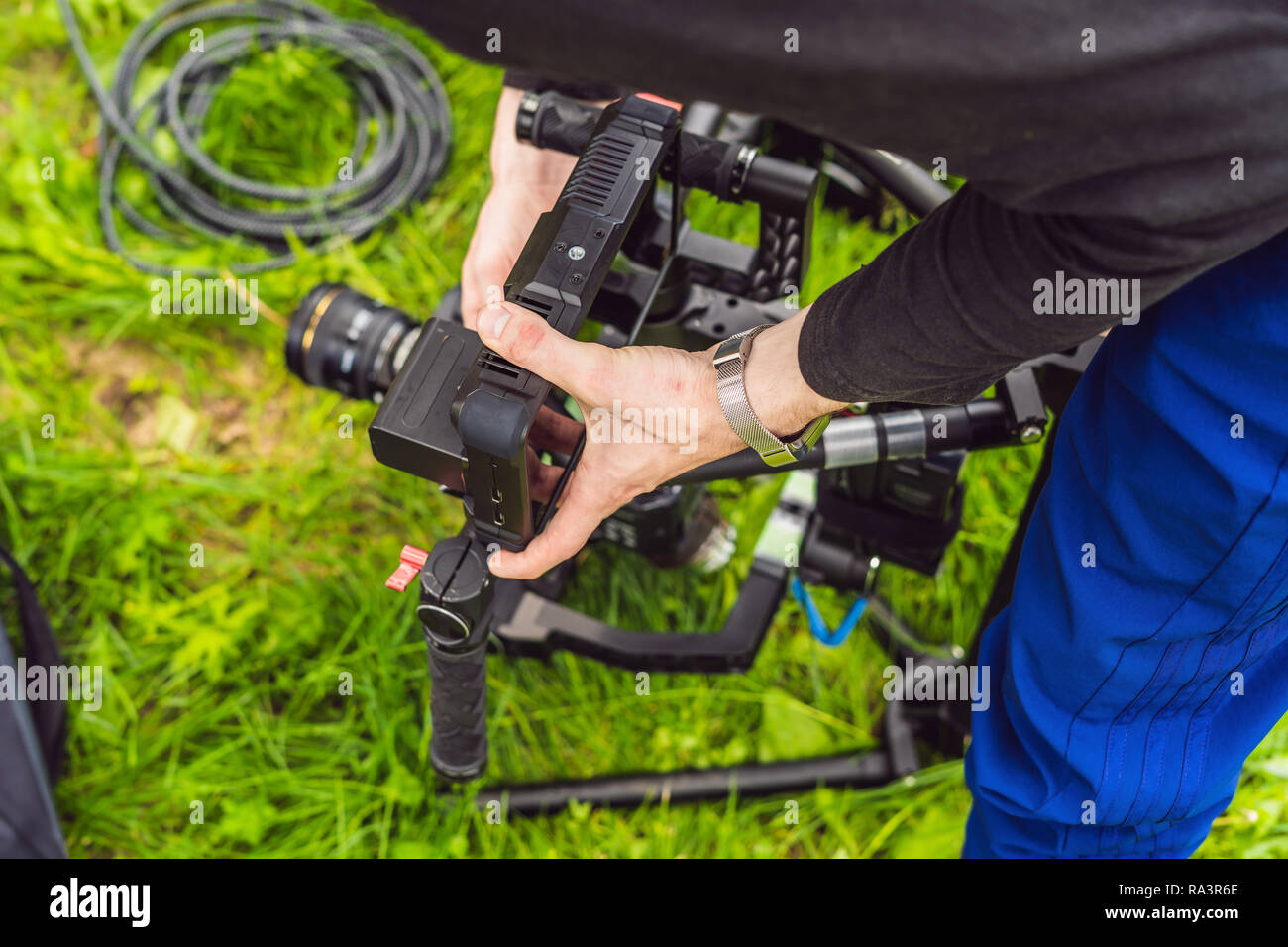 Cameraman setting up heavy duty professional 3axis gimbal stabilizer for cinema camera Stock