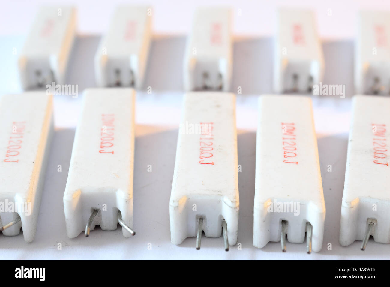 A heap of big ceramic white power resistors with 120 Ohm resistance and 5 Watt power dissipation, with vertical radial through hole mount, with pins Stock Photo