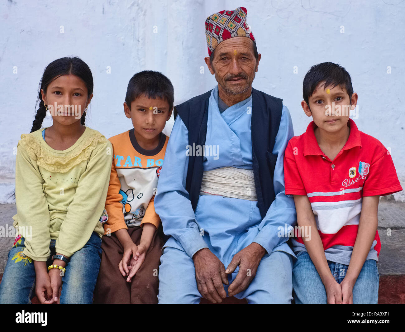 A family portrait in Kathmandu, Nepal, with the father in traditional Nepalese attire, and three children, minus the mother Stock Photo