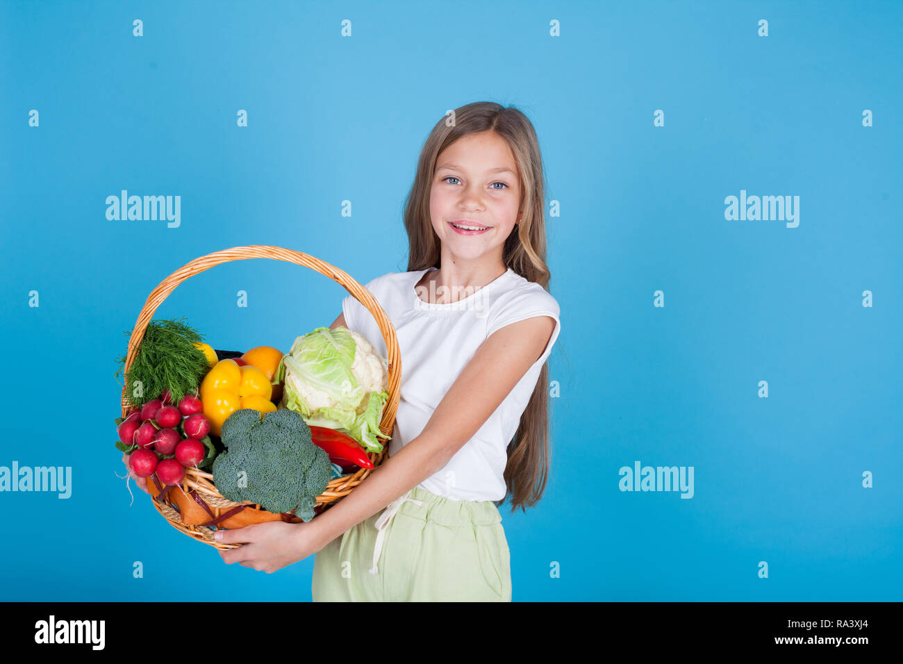 small beautiful girl holding a basket of fresh fruit and vegetables ...