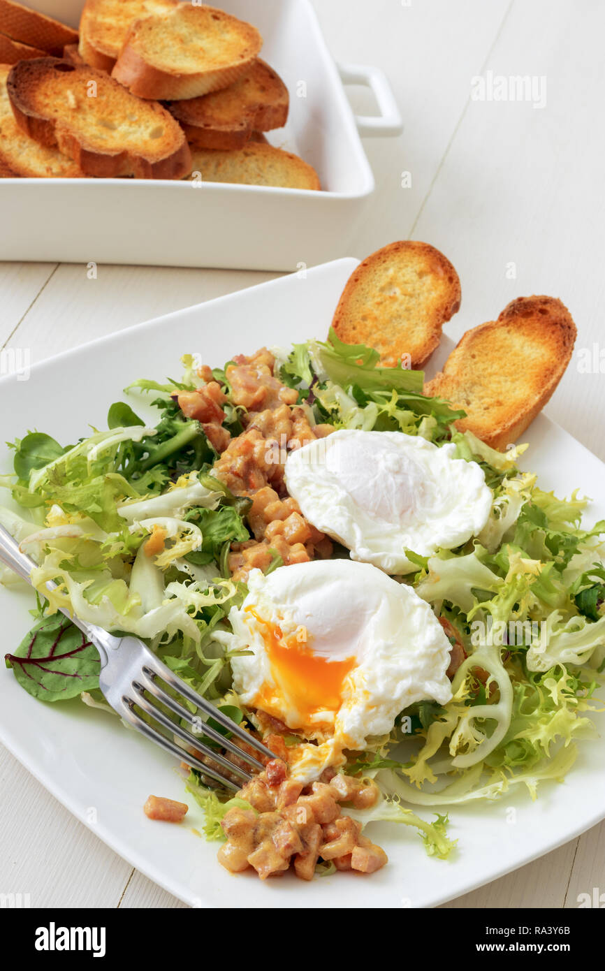 Classic French salad, great salad Lyonnaise. Dish with green leaves of