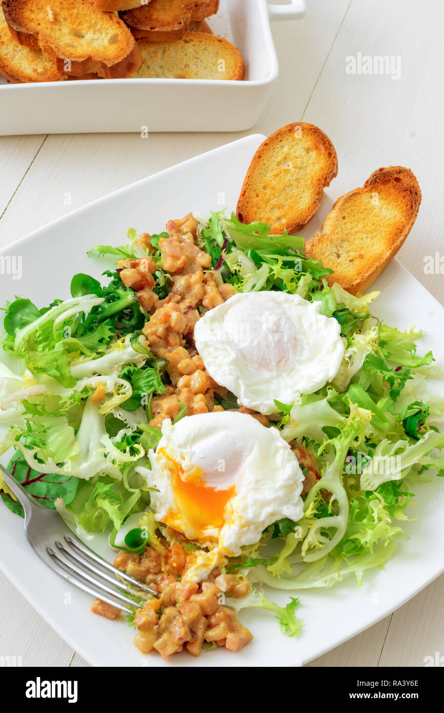Classic French salad, great salad Lyonnaise. Dish with green leaves of