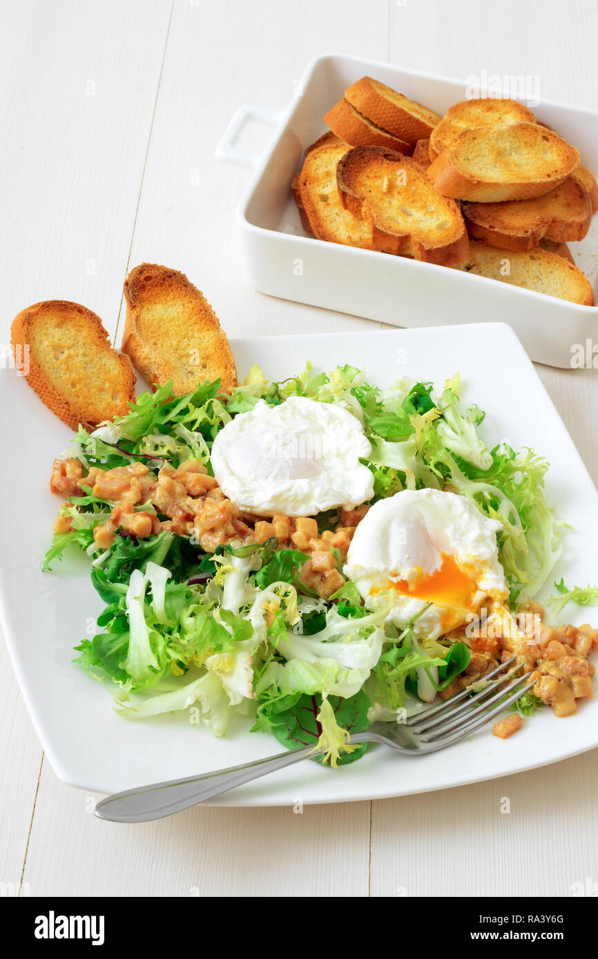 Classic French salad, great salad Lyonnaise. Dish with green leaves of