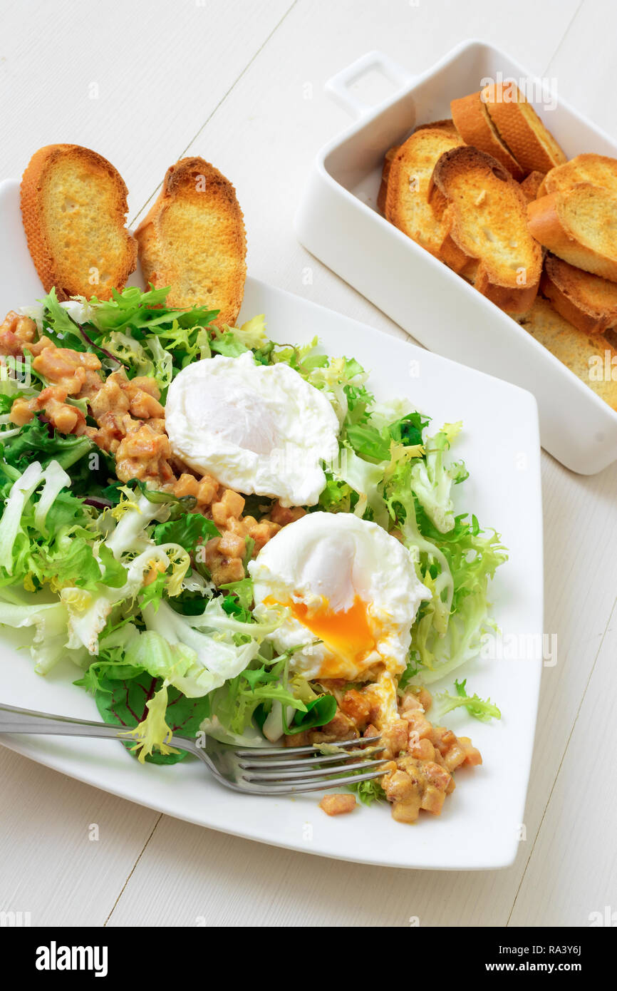 Classic French salad, great salad Lyonnaise. Dish with green leaves of