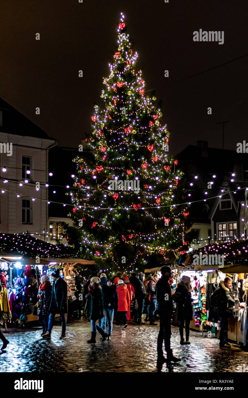 christmas tree fully decorated in central old town square with people walking in the market Stock Photo