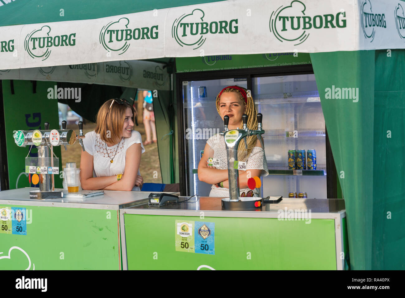 KIEV, UKRAINE - JULY 08, 2018: Young woman bartenders work in Tuborg beer outdoor bar at the Atlas Weekend Festival in National Expocenter. Tuborg is  Stock Photo