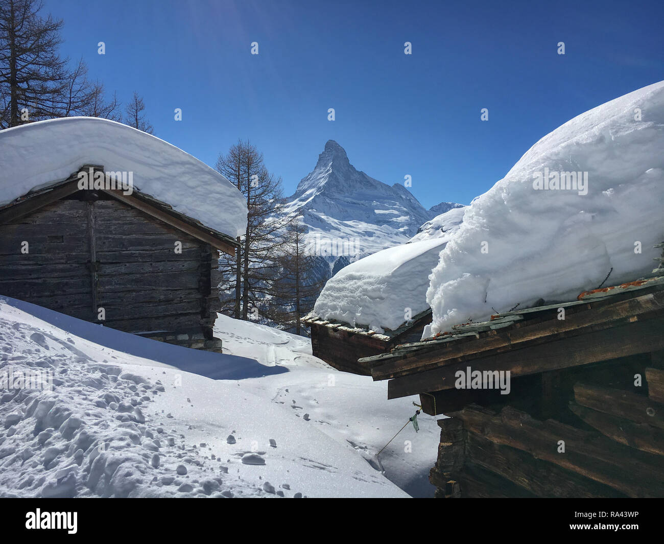 Cottages with lots of snow on the rooftop in front of Matterhorn ...