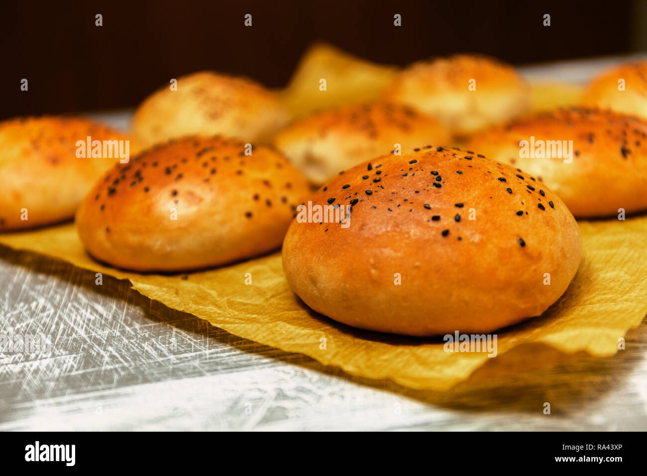 Freshly baked burger buns with black sesame on a baking paper. Fresh