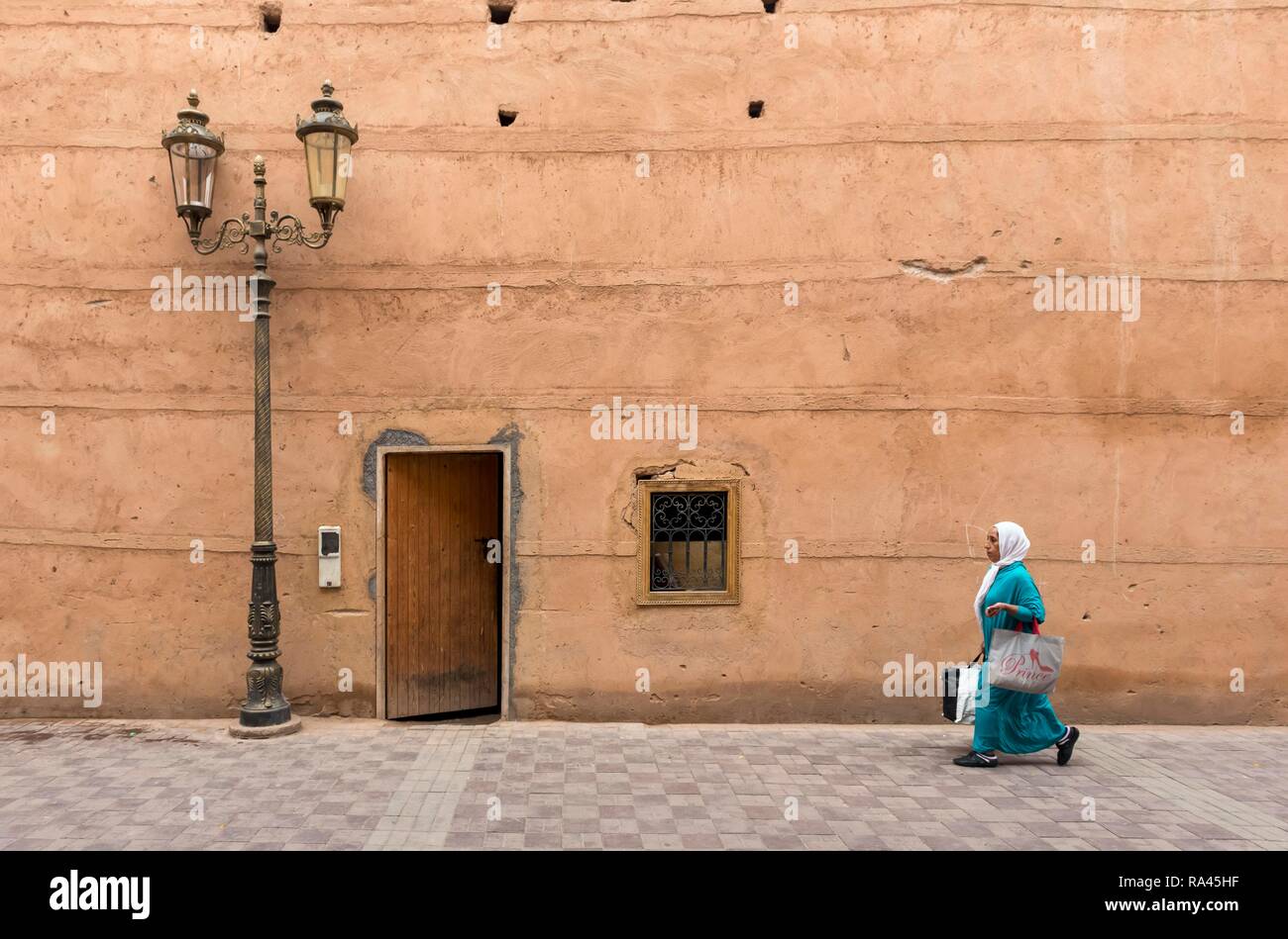 Woman walks along clay walls of Badi Palace in Marrakech, Morocco Stock Photo